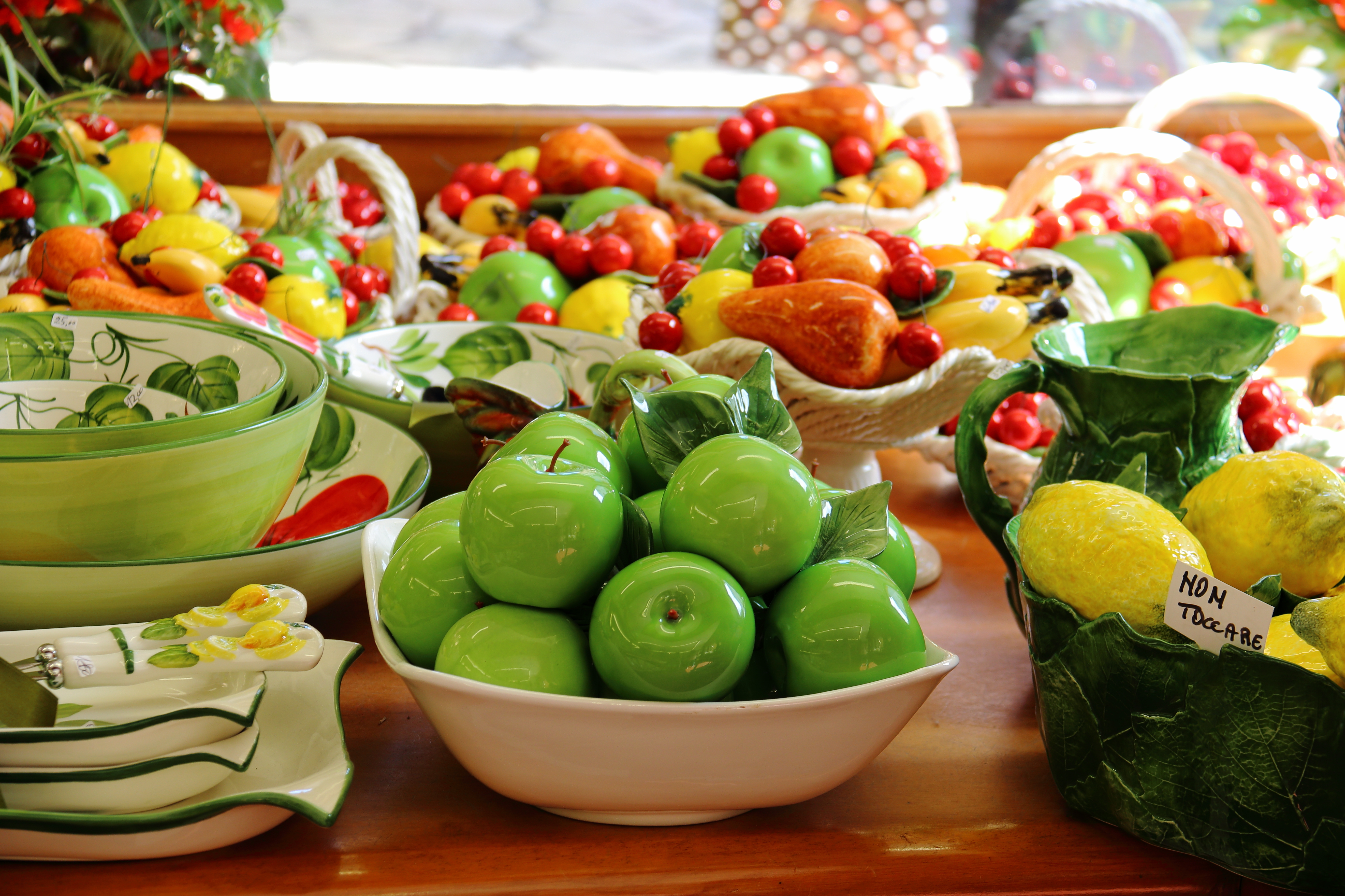 Farverige italienske keramikfade med håndmalede frugtmotiver, typisk kunsthåndværk fra Gardasøen-regionen