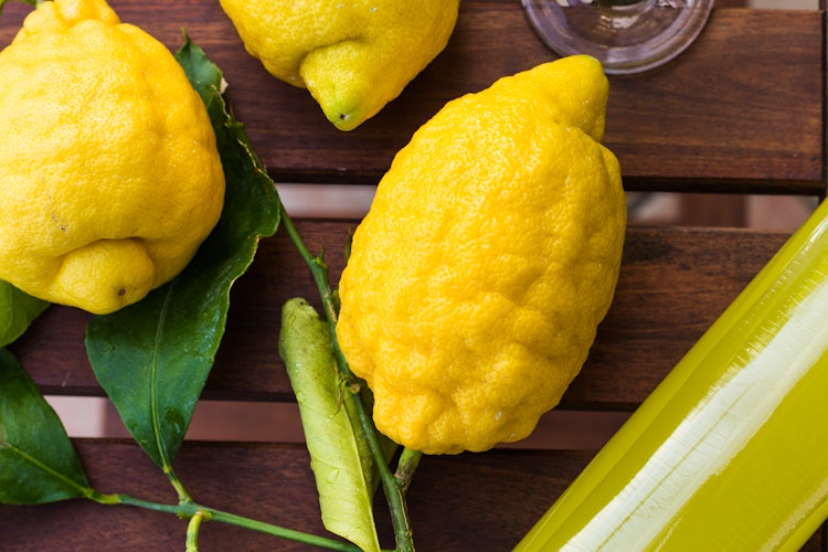 Traditionel italiensk limoncello med friske citroner serveret på terrasse i Amalfi - en forfriskende smagsoplevelse på din rejse til Italien