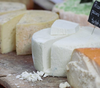 Farverig udstilling af traditionelle italienske oste på det lokale marked i Alba, perfekt for madentusiaster på gourmetrejse i Italien