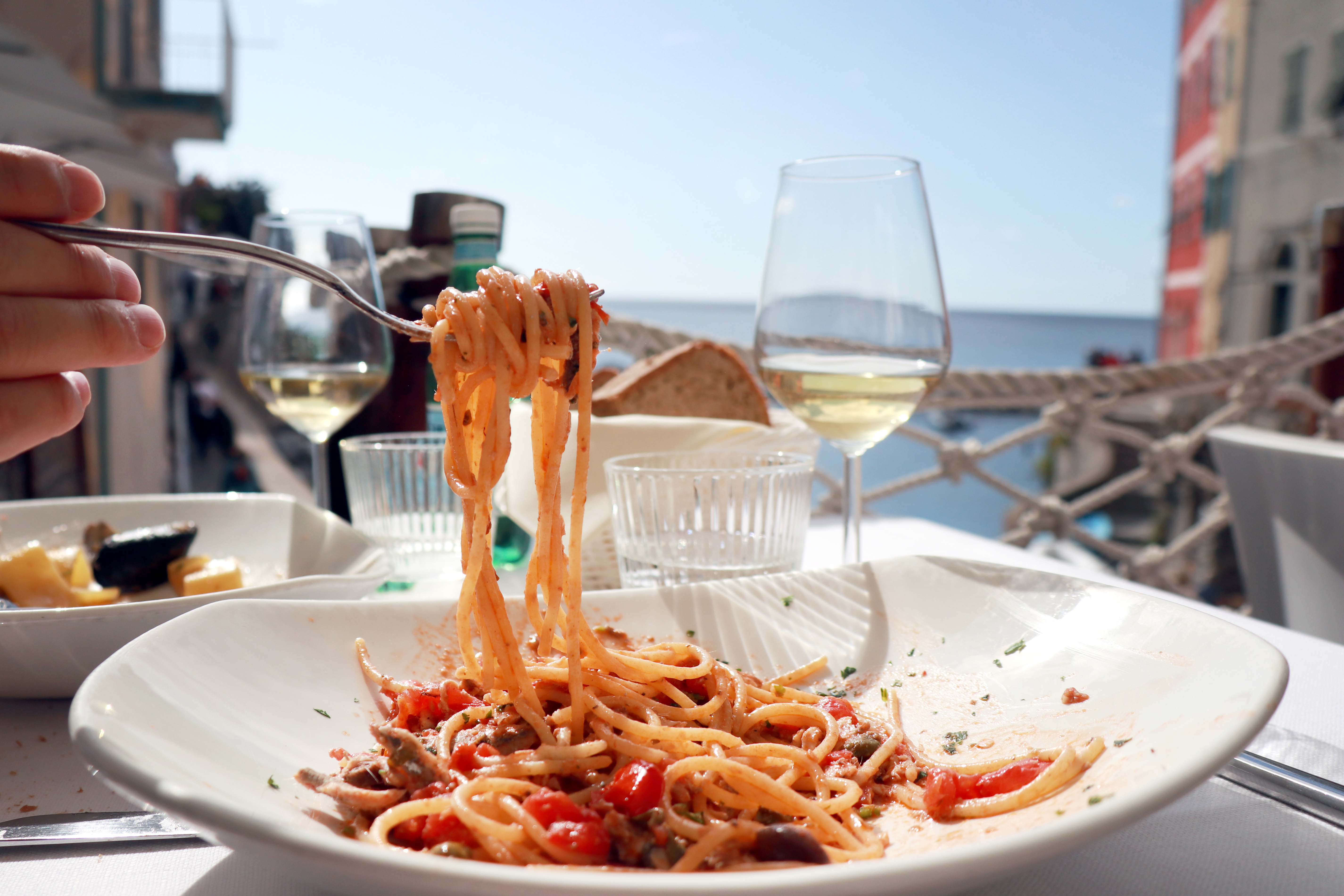 Lækker italiensk pastaret serveret med hvidvin på en eksklusiv restaurant med havudsigt i Cinque Terre, den perfekte kulinariske oplevelse under en sommerferie i Italien