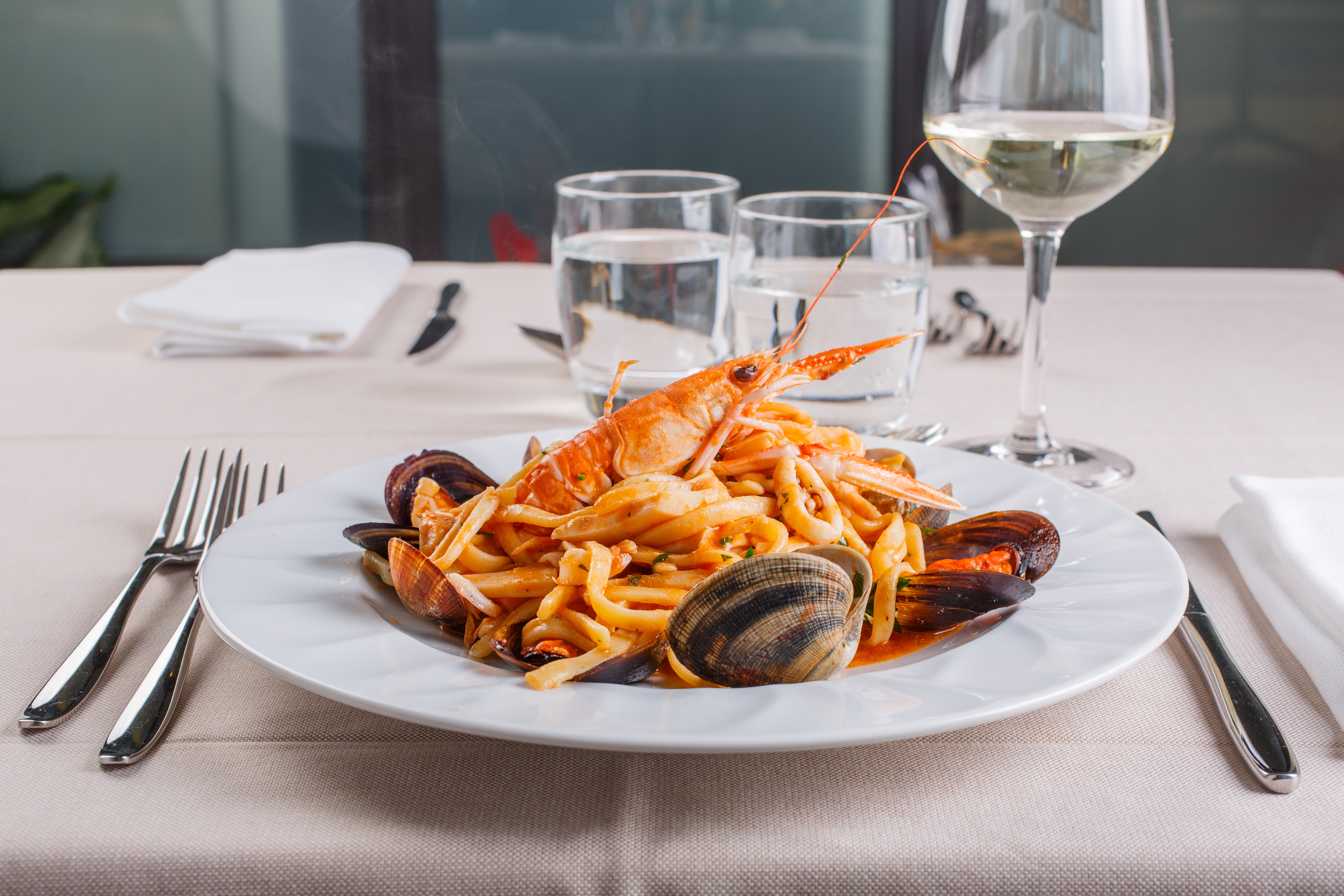 Lækker italiensk Scialatielli seafood pasta med muslinger, blåmuslinger, jomfruhummer og blæksprutte serveret på en elegant restaurant ved Middelhavet