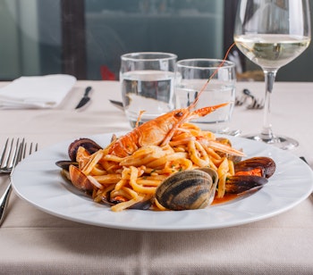 Lækker italiensk Scialatielli seafood pasta med muslinger, blåmuslinger, jomfruhummer og blæksprutte serveret på en elegant restaurant ved Middelhavet