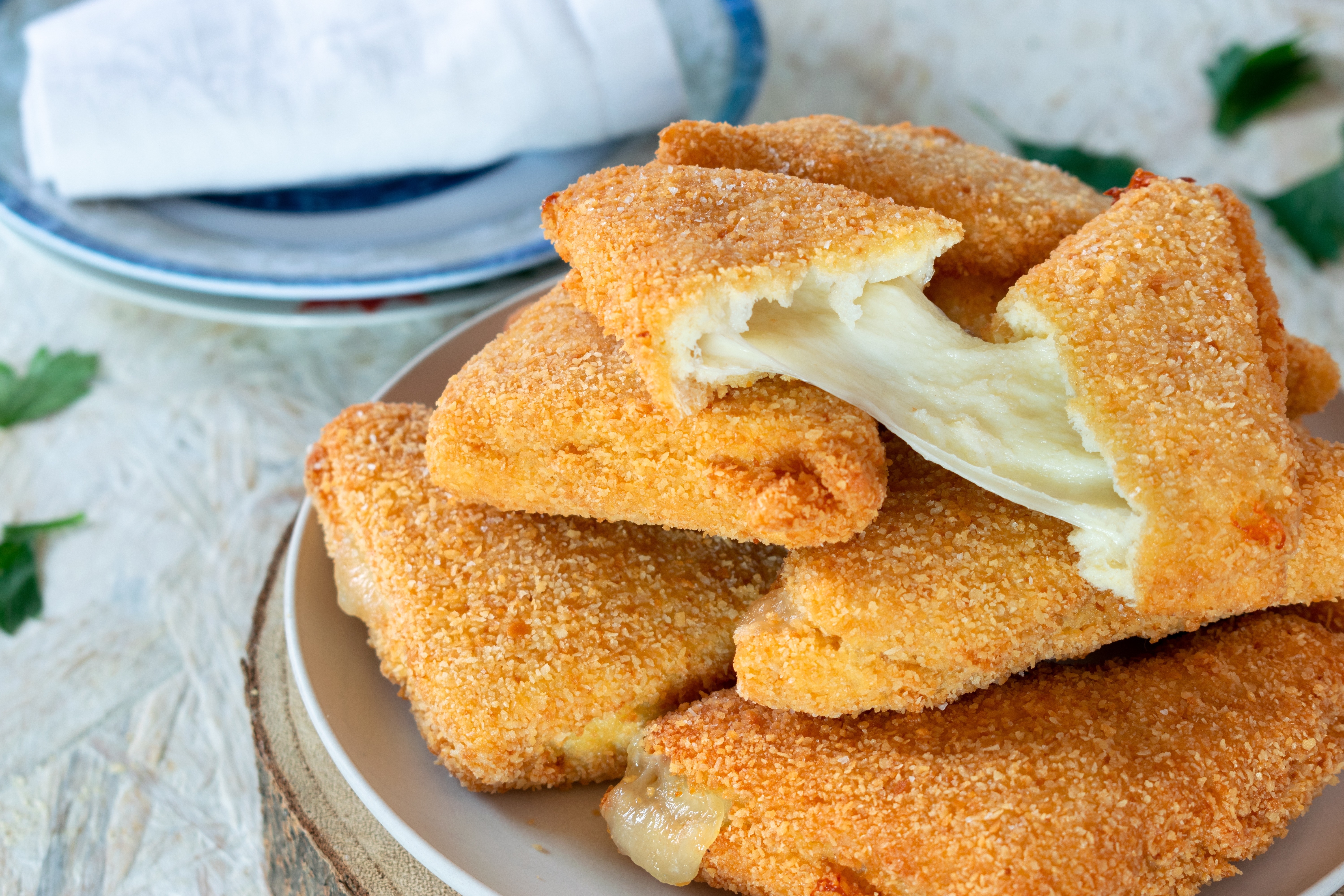 Traditionel italiensk mozzarella in carrozza - sprødt friturestegt brød fyldt med smeltet mozzarella ost, serveret på en tallerken
