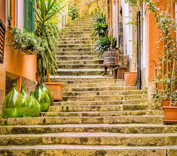 Farverige stentrapper i pittoresk italiensk landsby med traditionelle orange og gule huse