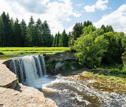 Det imponerende Jagala-vandfald, Estlands bredeste og mest kraftfulde naturlige vandfald, der falder majestætisk ned over klippeafsatser omgivet af frodig skov i det nordlige Estland