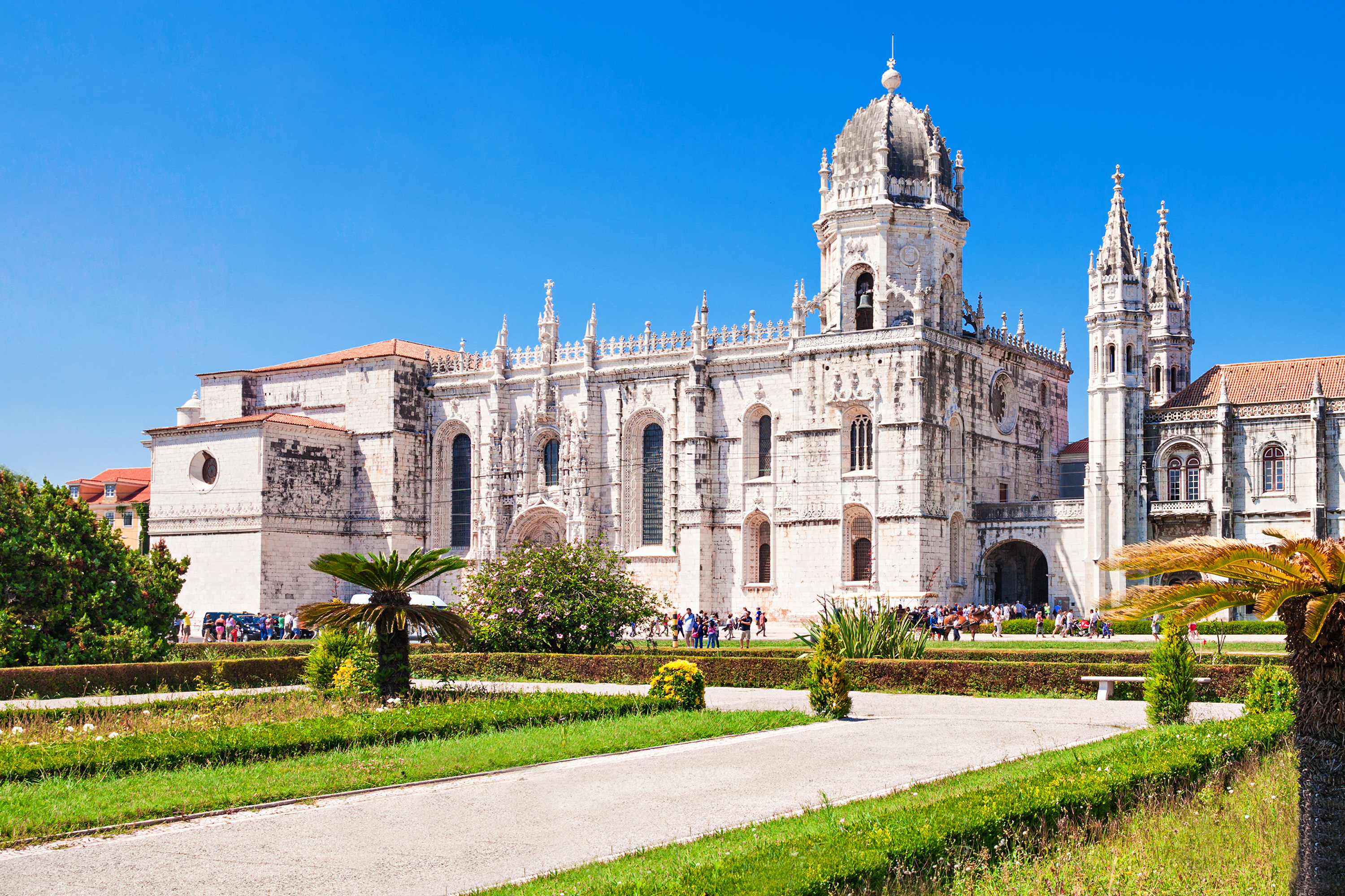 Det historiske Jeronimos Kloster i Lissabon med imponerende Manuelisk arkitektur, dekorativ hvid facade og velholdte haver under blå himmel - UNESCO verdensarv