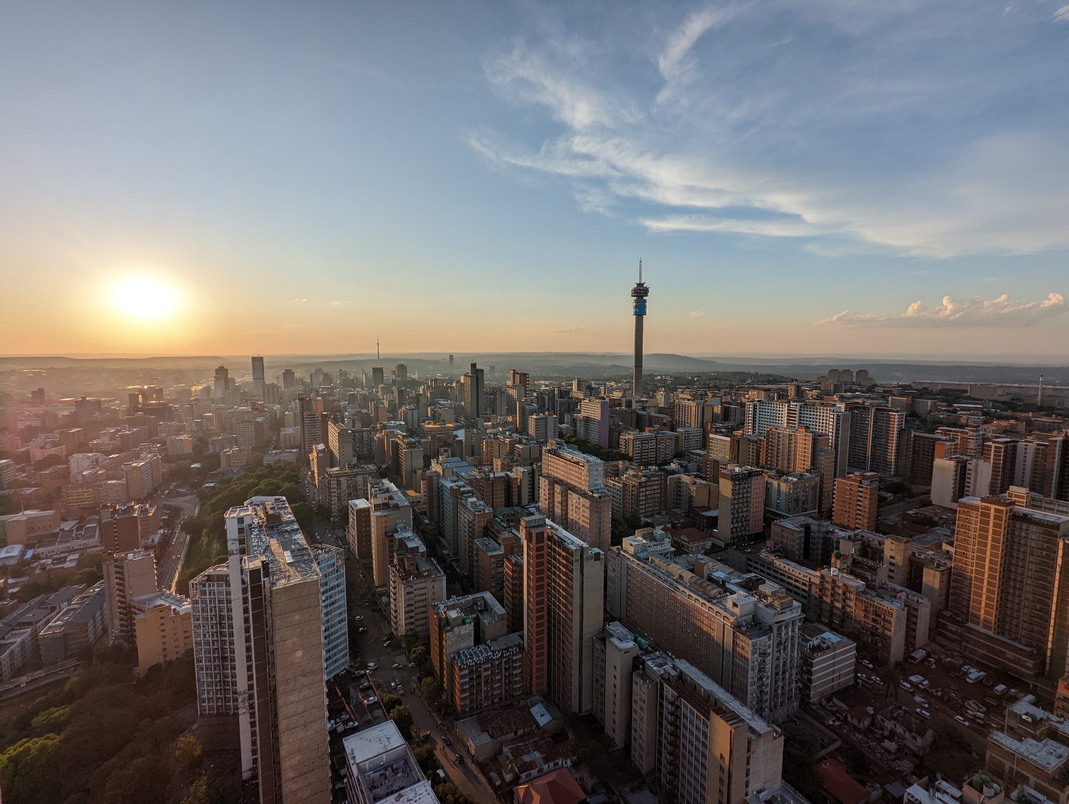 Luftfoto af Johannesburgs byhorisont ved solnedgang med Hillbrow Tower og moderne bygninger