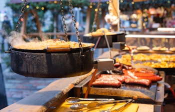 Traditionelle madboder på det festlige julemarked i Tallinn, Estland med hængende gryder og grillede specialiteter i vintermørket