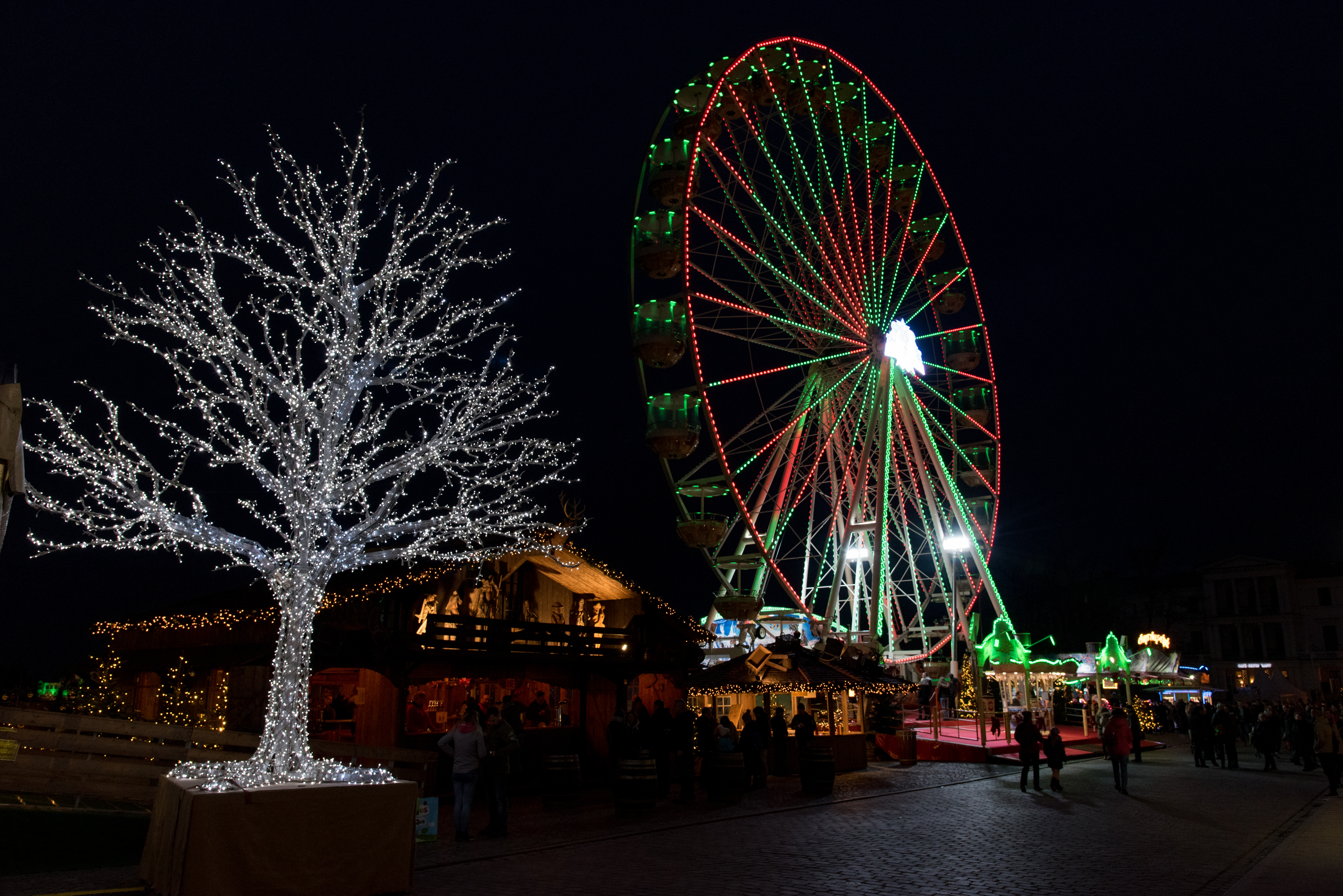 Julemarked om natten med oplyst pariserhjul og festlige lys i tysk bycentrum