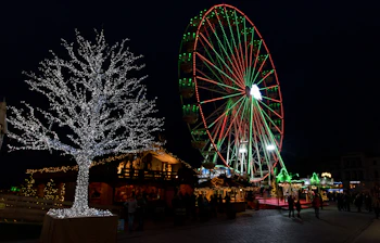 Julemarked om natten med oplyst pariserhjul og festlige lys i tysk bycentrum
