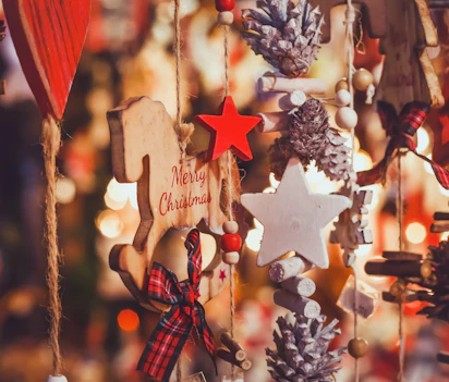 Julepynt på julemarked med Merry Christmas ornament, træstjerner, kogler og festlige lys