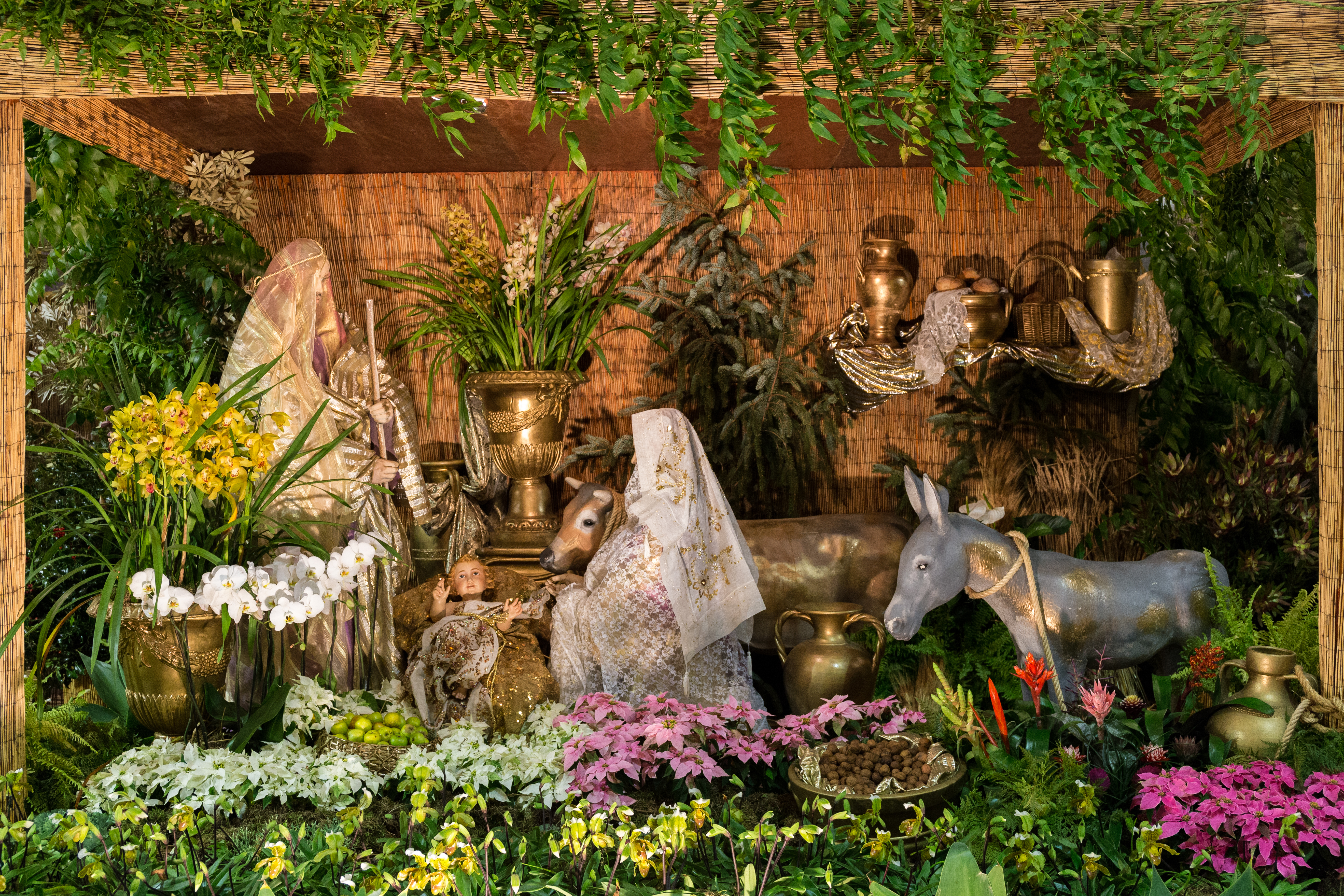 Traditionel julekrybbe med Maria, Josef og Jesusbarnet i rustik stald med blomster og keramik