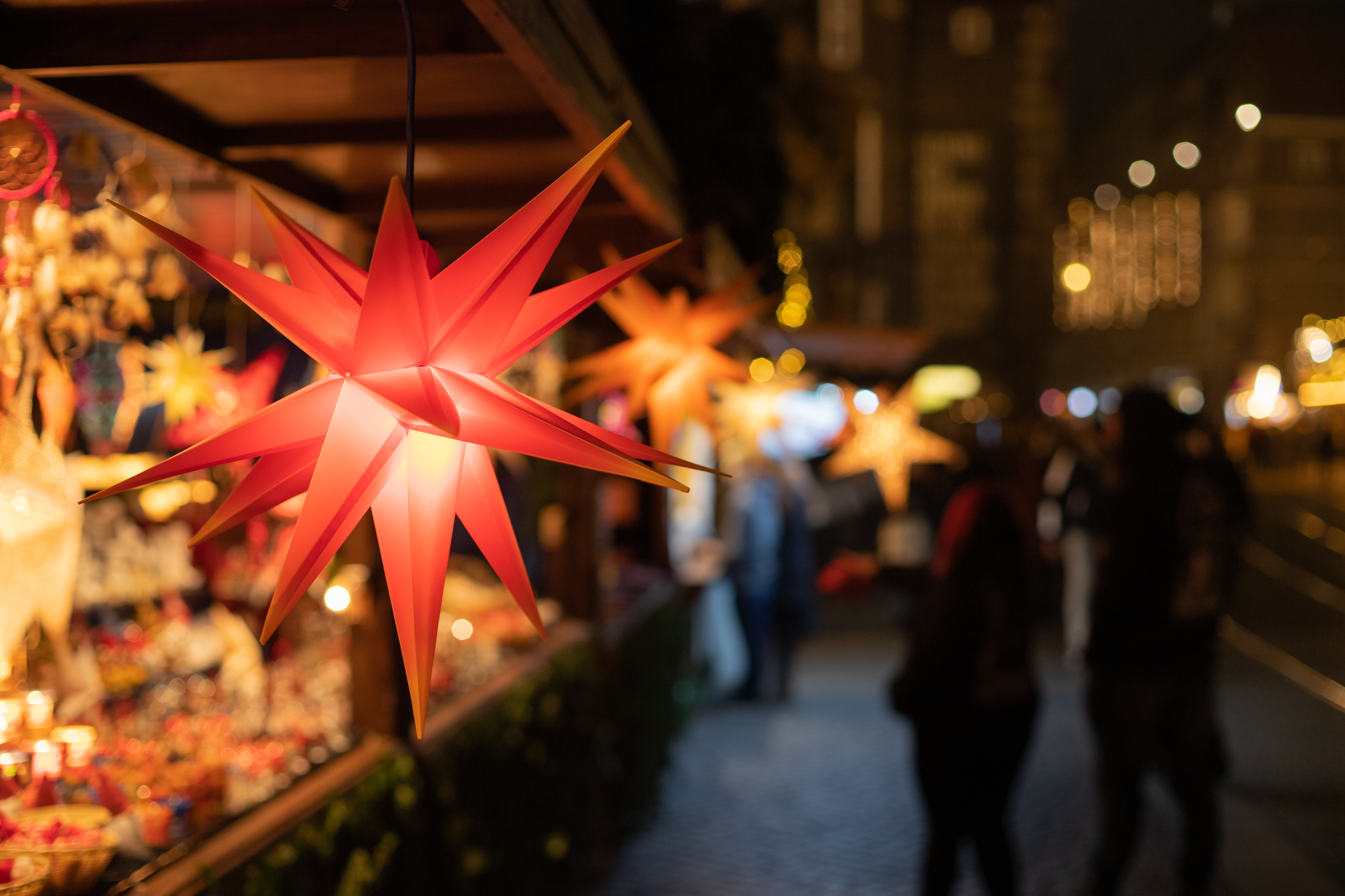 Rød oplyst julestern på traditionelt tysk julemarked med hyggelige boder og varm belysning