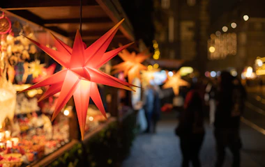 Rød oplyst julestern på traditionelt tysk julemarked med hyggelige boder og varm belysning