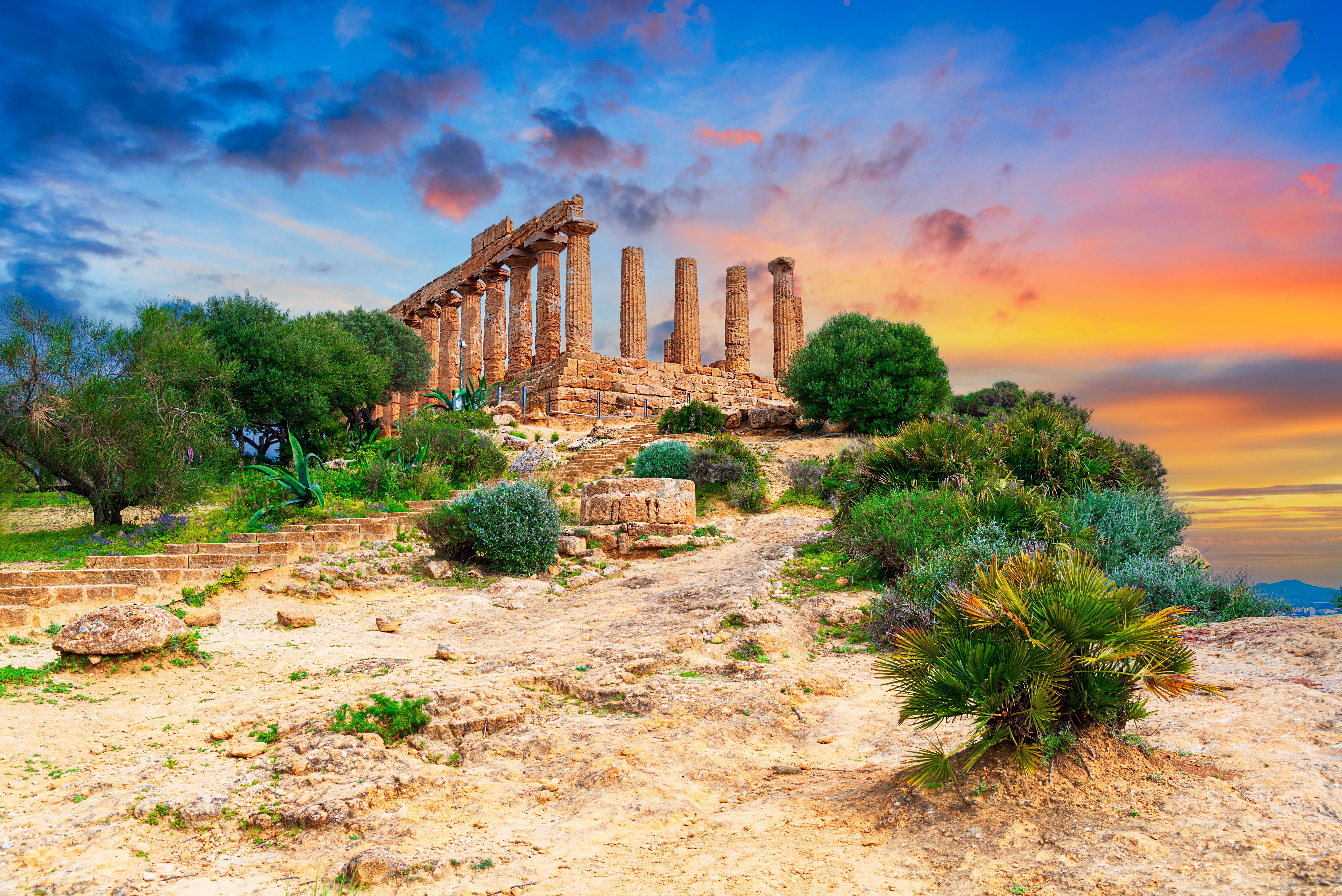 Det antikke Juno-tempel ved solnedgang i Tempeldalen, Agrigento på Sicilien med dramatisk orange og blå himmel