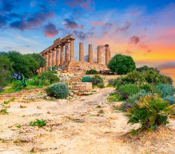 Det antikke Juno-tempel ved solnedgang i Tempeldalen, Agrigento på Sicilien med dramatisk orange og blå himmel