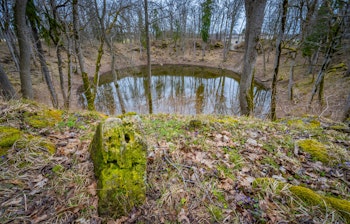 Kaali meteoritkrater med spejlblankt vand i Saaremaa, Estland - en fascinerende geologisk formation og populær turistattraktion