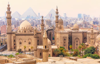 Luftudsigt over Kairo med Sultan Hassan-moskeen, middelalderlige minareter og Giza-pyramiderne i baggrunden