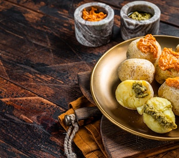 Traditionel kanarisk specialitet Papas Arrugadas (rynkede kartofler) med krydret rød Mojo picon sauce serveret på træbaggrund