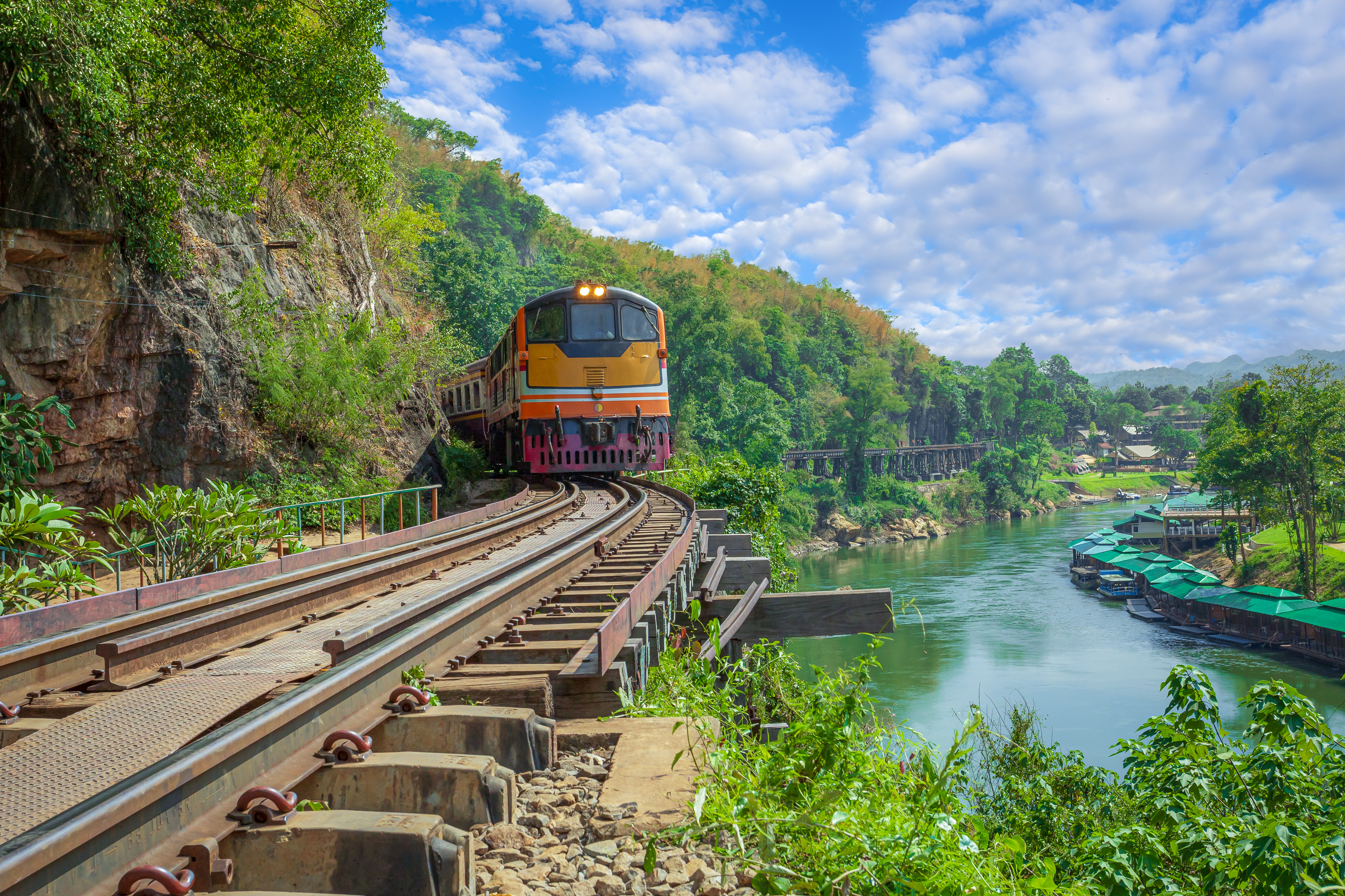 Historisk tog på Dødsbanens bro over River Kwai i Kanchanaburi Thailand med frodig tropisk natur