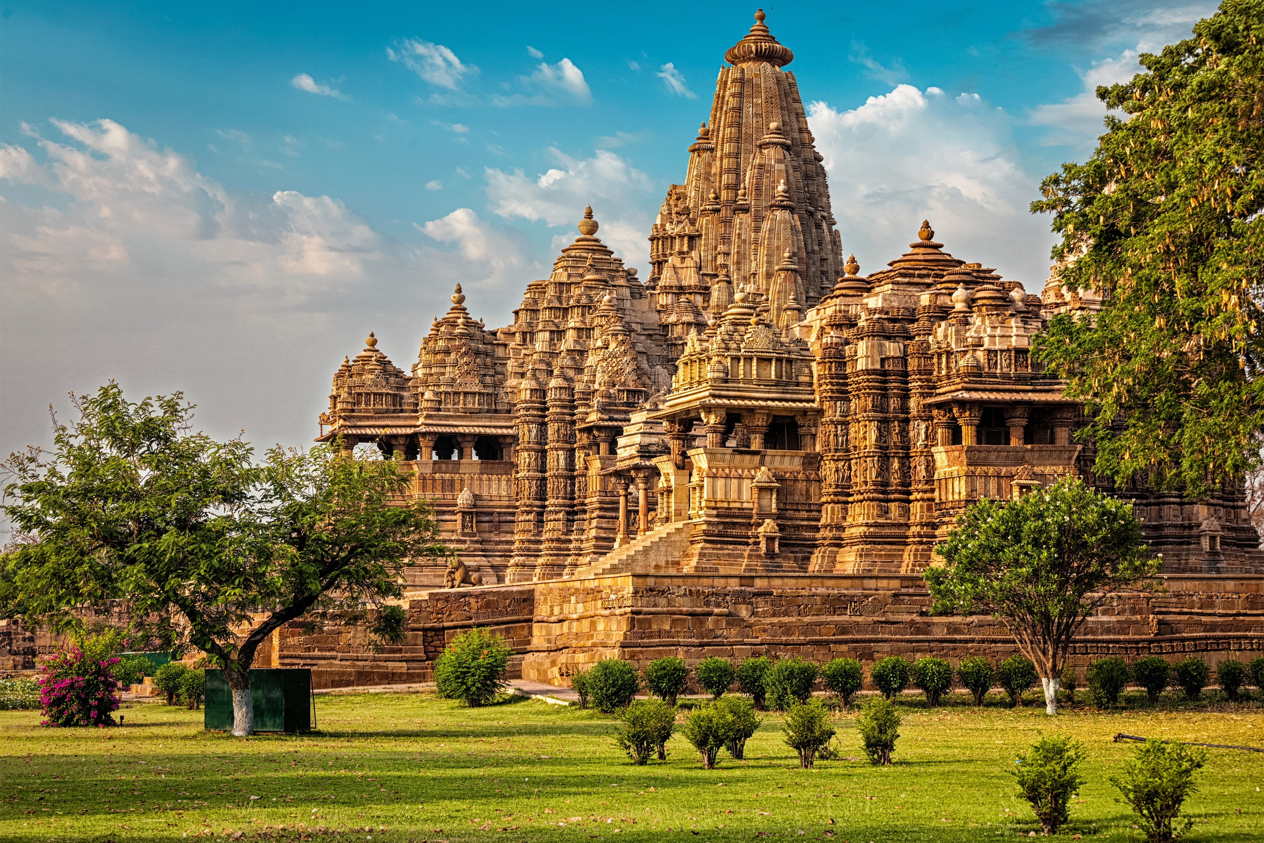 Det storslåede Kandariya Mahadev-tempel i Khajuraho, Madhya Pradesh, Indien – et UNESCO Verdensarvsted med detaljerede hinduistiske stenudskæringer og tårnende spir mod en blå himmel