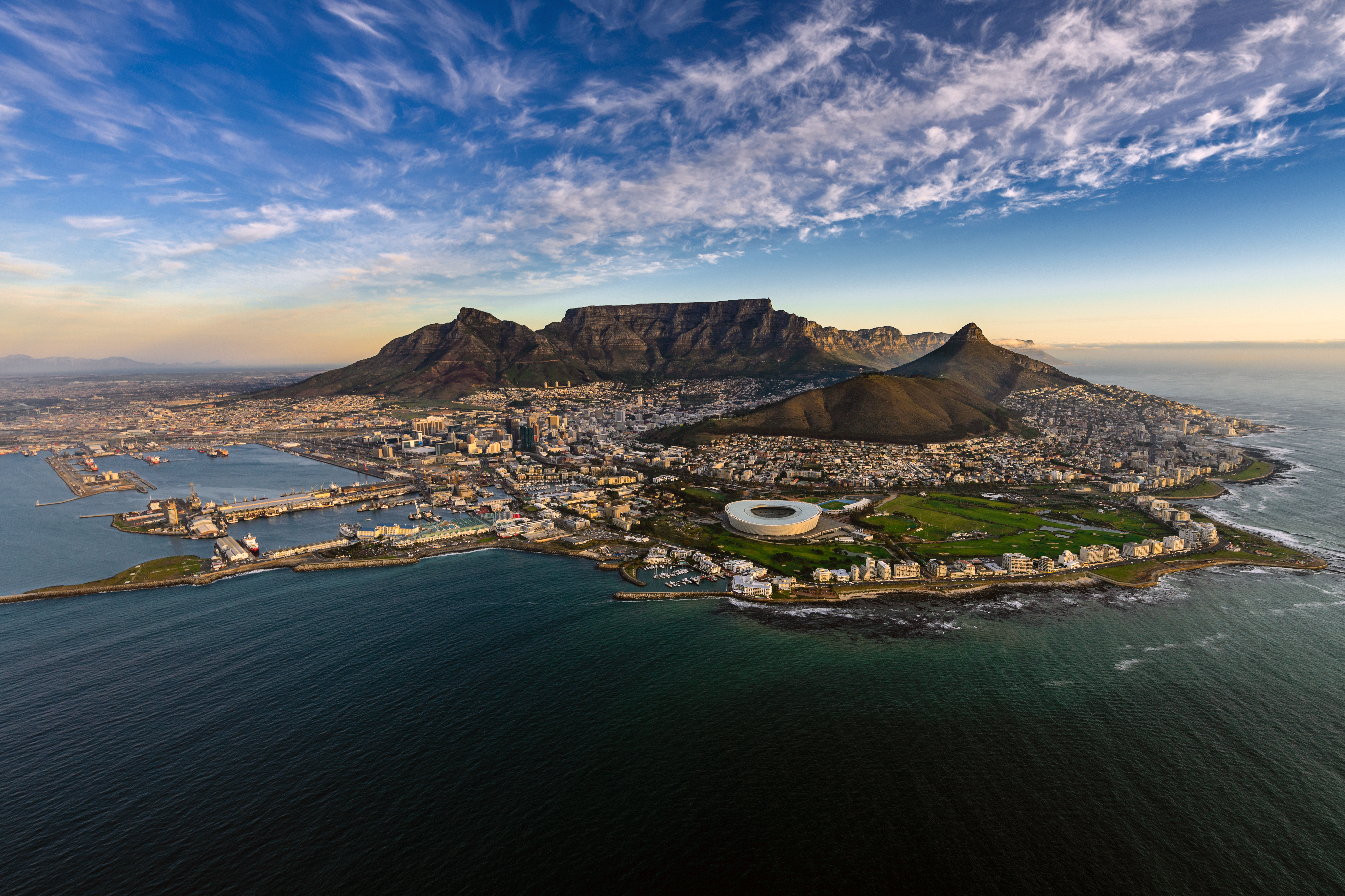 Luftfoto af Kapstaden med Table Mountain og stadion omgivet af ocean ved solnedgang