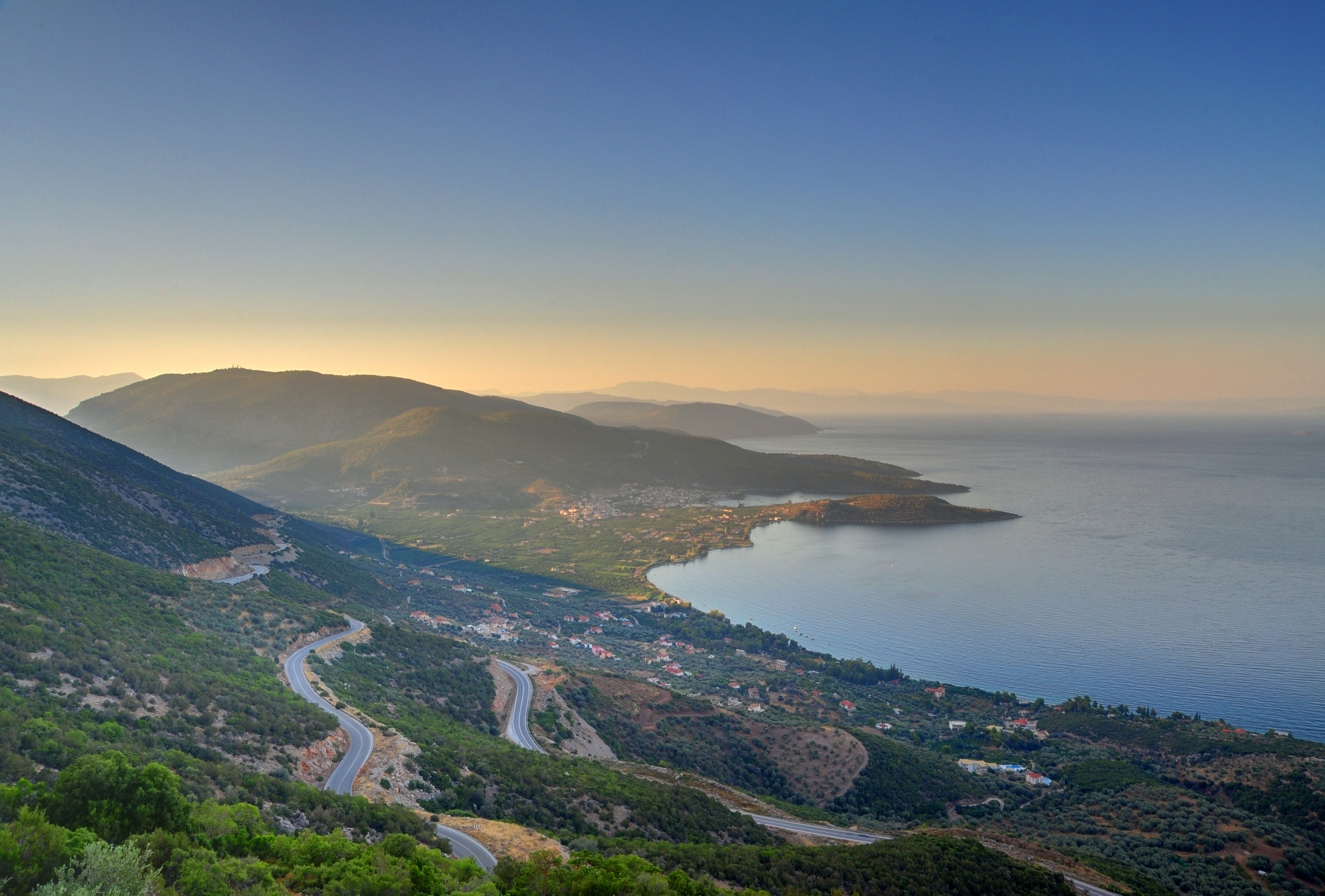 Idyllisk udsigt over Karathonas-bugten nær Nafplio med snoede veje langs den græske middelhavskyst og bjerge i baggrunden