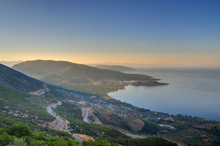 Idyllisk udsigt over Karathonas-bugten nær Nafplio med snoede veje langs den græske middelhavskyst og bjerge i baggrunden