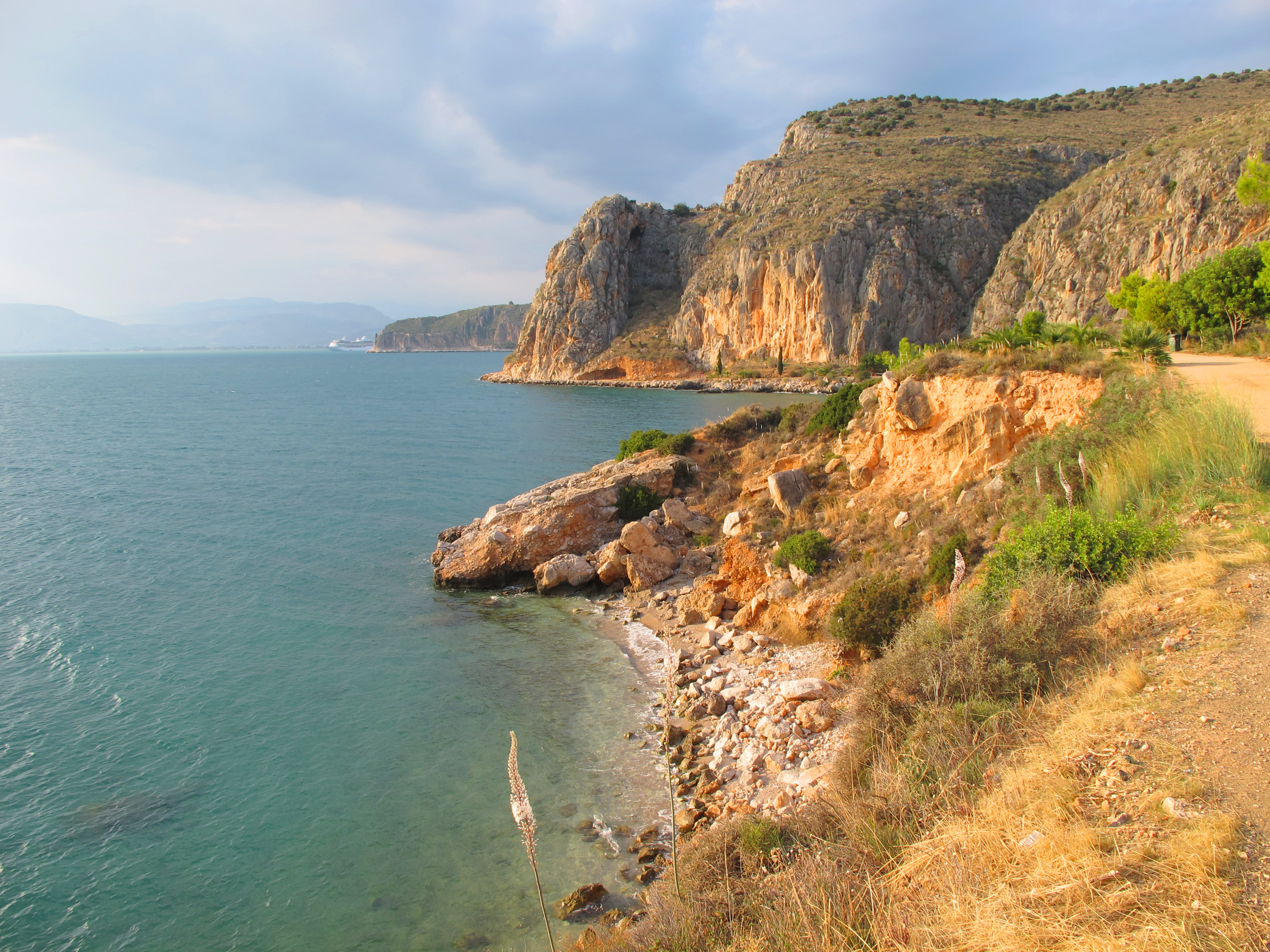 Smuk klippekyst ved Karathonas strand med udsigt til Arvanitia-bakken og Nafplio, Peloponnes, Grækenland