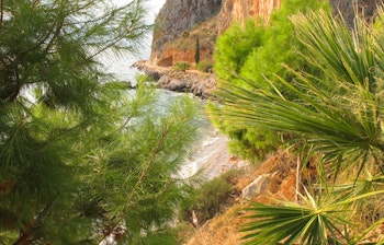 Betagende udsigt over den klipperige kystlinje ved Karathonas strand med Arvanitia-bakken i baggrunden nær den historiske by Nafplio på Peloponnes