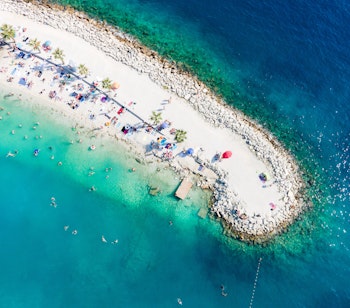Luftfoto af Kasjuni strand med turkisblåt vand ved Split i Kroatien