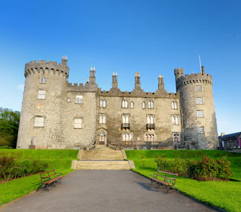 Kilkenny Castle med to karakteristiske tårne og velplejet grønt parkanlæg i Kilkenny, Irland