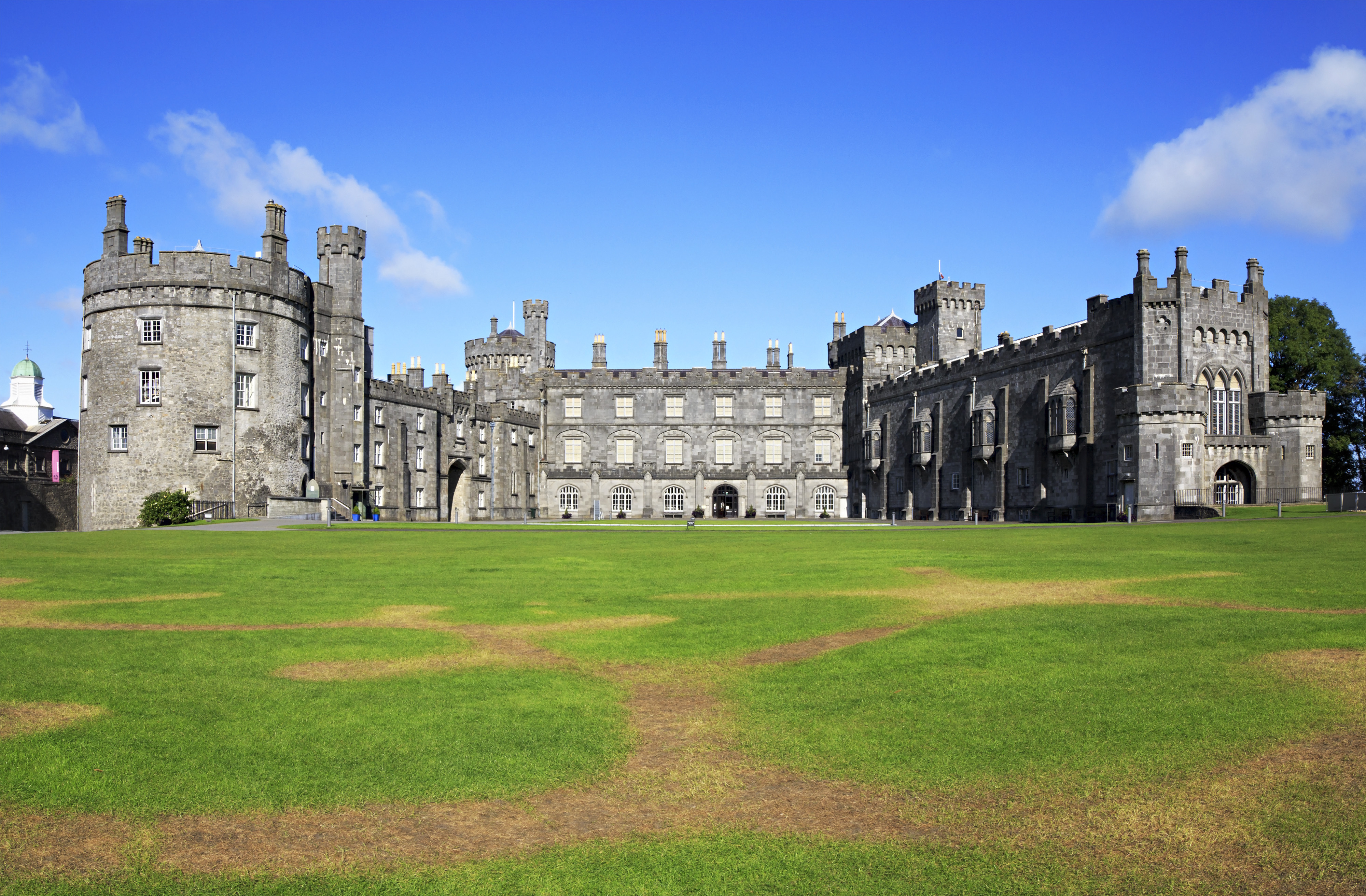 Historiske Kilkenny Slot med middelalderlige tårne og grøn gårdsplads i Irland