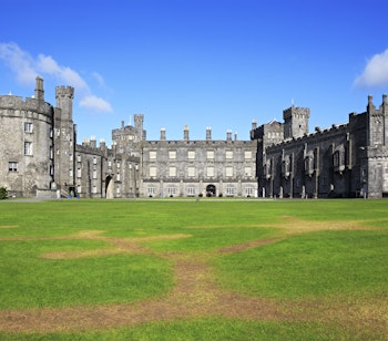 Historiske Kilkenny Slot med middelalderlige tårne og grøn gårdsplads i Irland