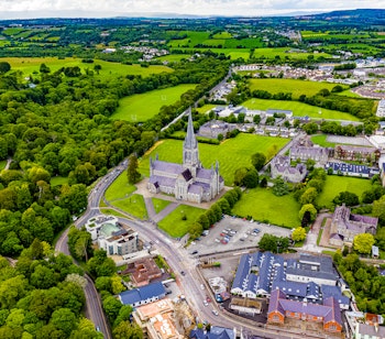 Luftfoto af den historiske Killarney domkirke og by omgivet af grønne marker i County Kerry Irland