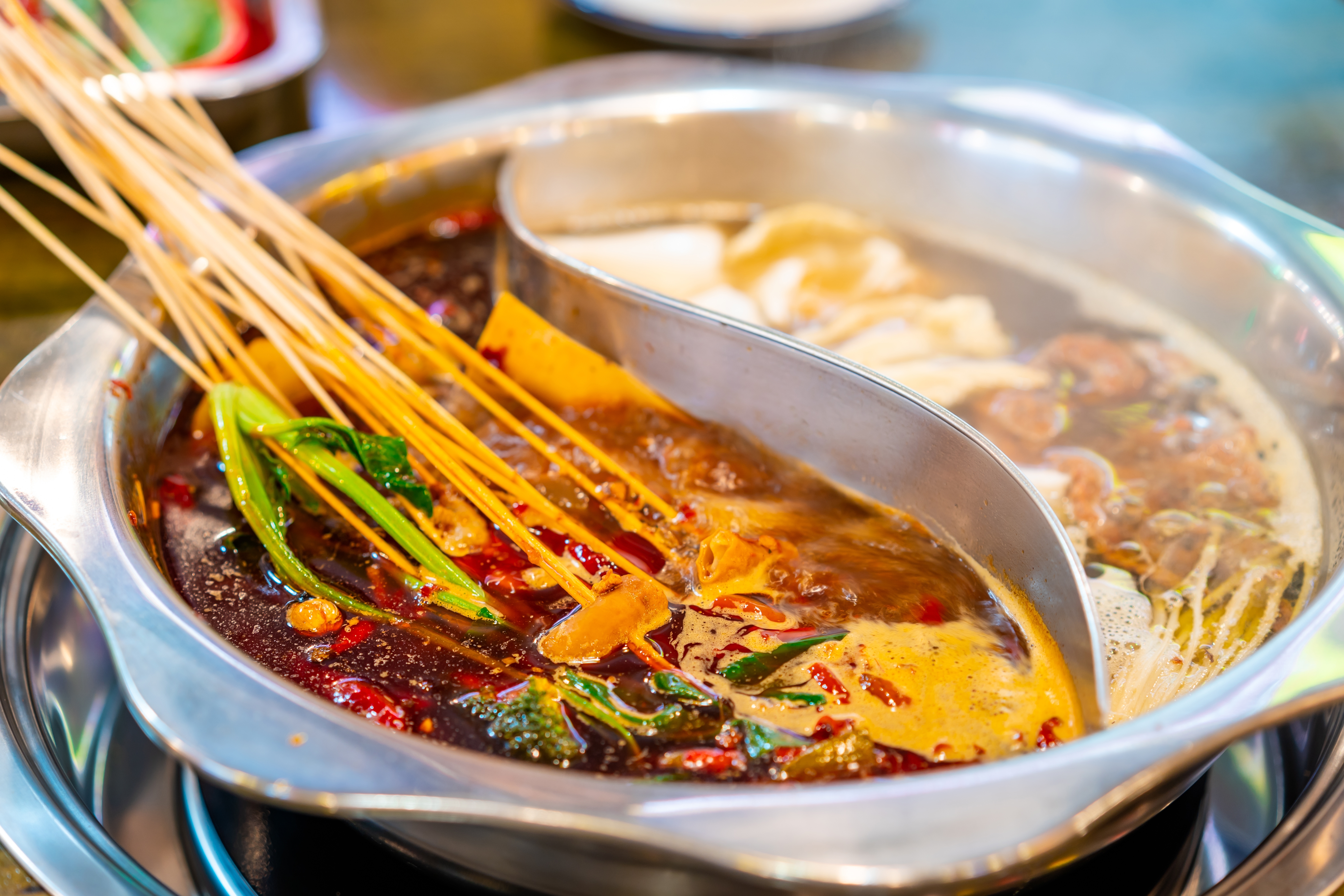 Traditionel kinesisk hot pot med bambusspyd i krydret roed buillon og mild hvid buillon i autentisk Chengdu restaurant