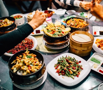 Traditionel kinesisk middag med Beijing and og forskellige retter på rundt restaurantbord