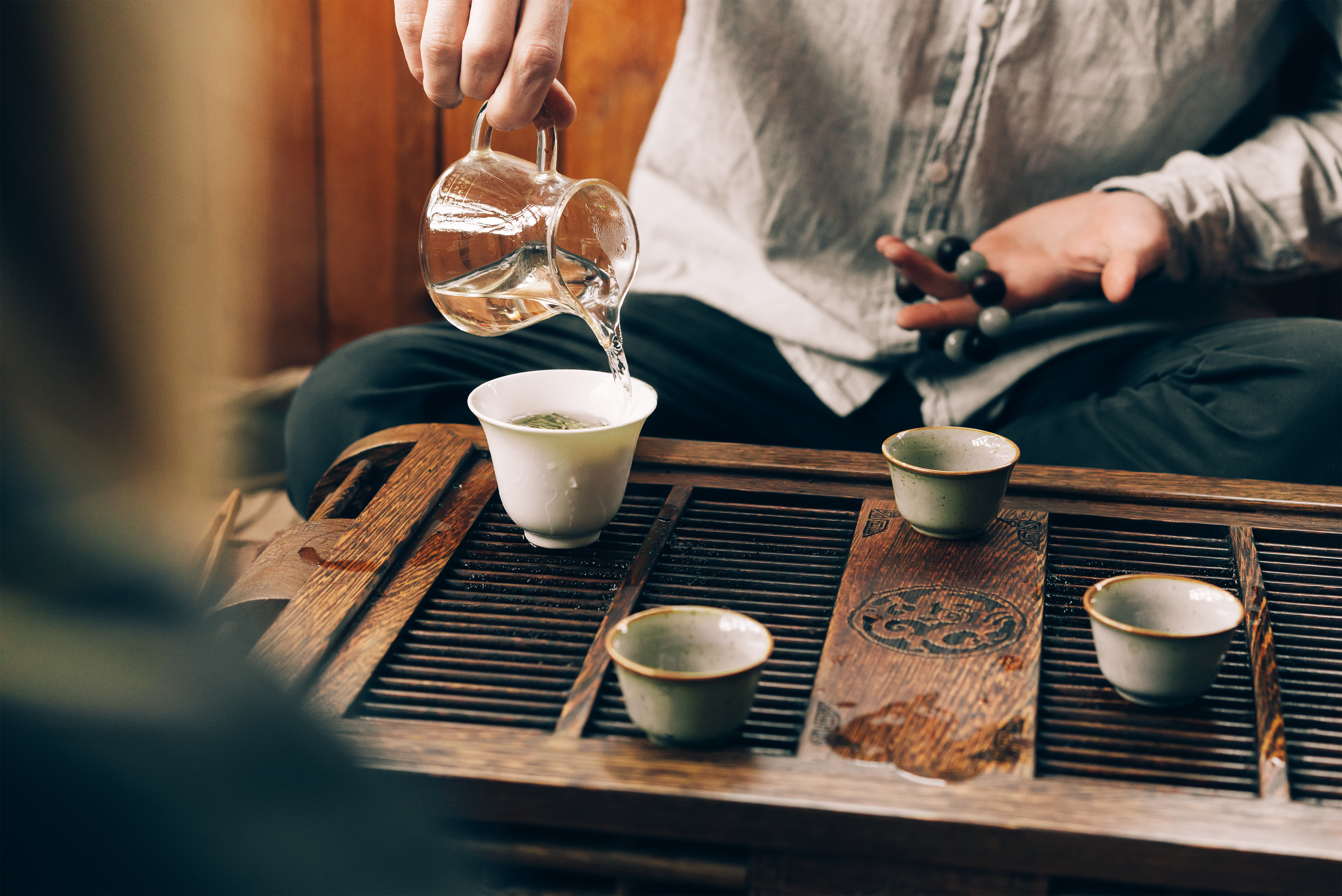 Traditionel kinesisk te-ceremoni med keramikkopper på bambusbakke i naturligt sollys