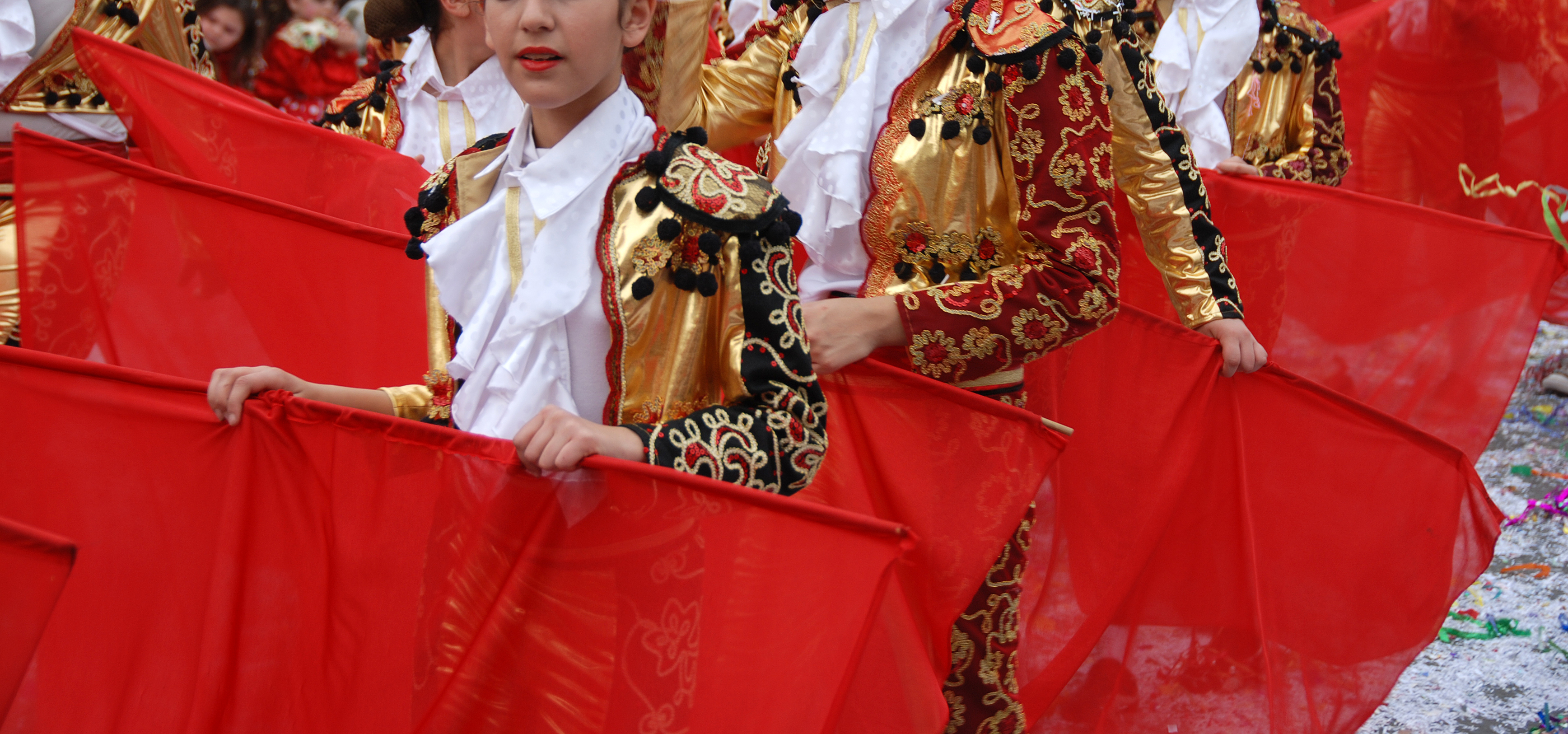 Kinesiske dansere i guldne kostumer udfører traditionel dans med røde silkesjaeler ved kulturfestival