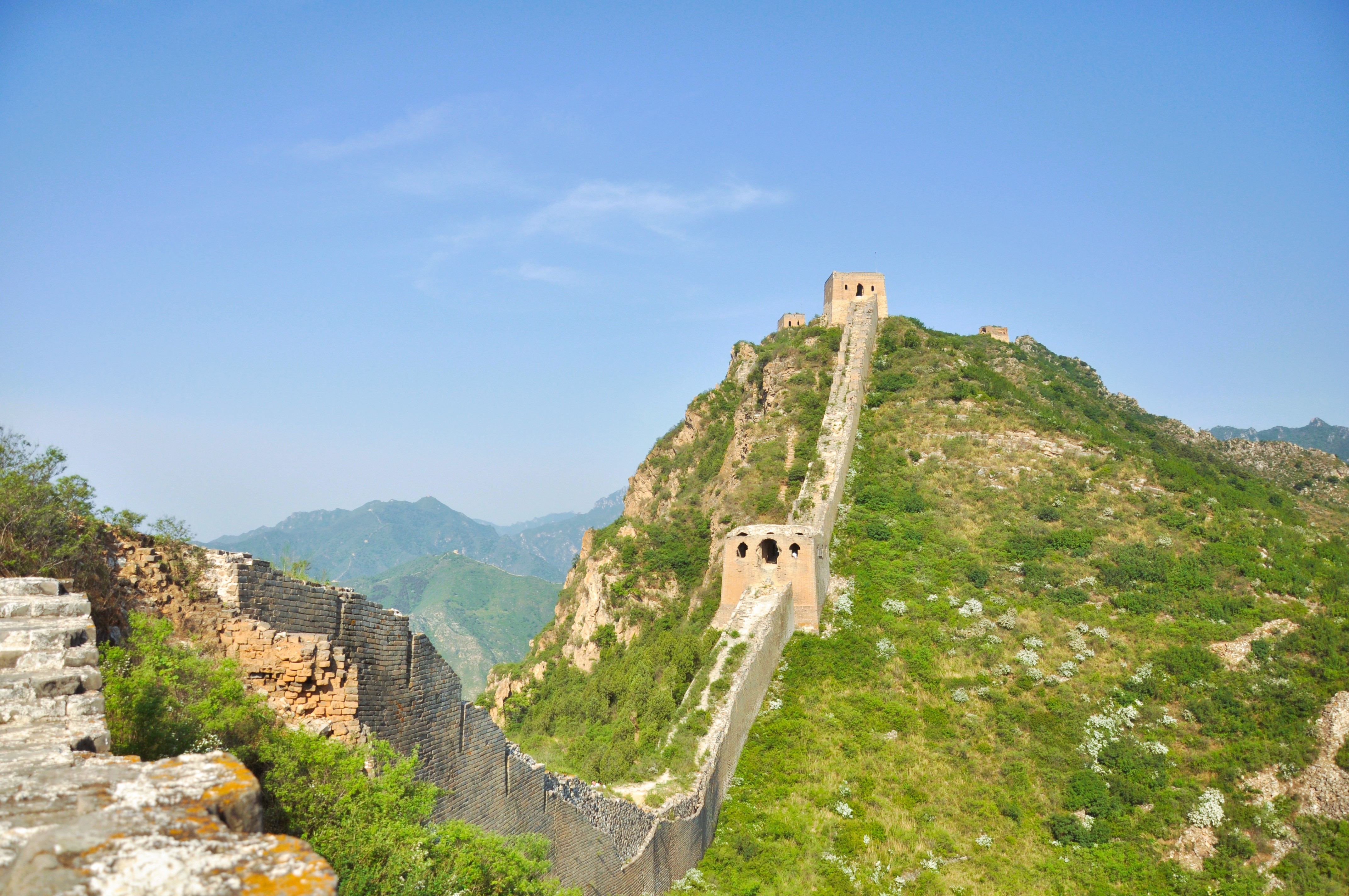Den Kinesiske Mur slynger sig gennem groenne bjerge nær Beijing med historiske vagttaarne
