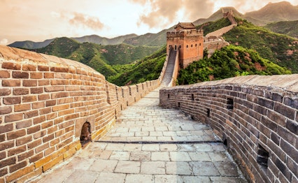 Den Kinesiske Mur slynger sig gennem groenne bjerge ved solnedgang - beroemte historiske vartegn i Beijing