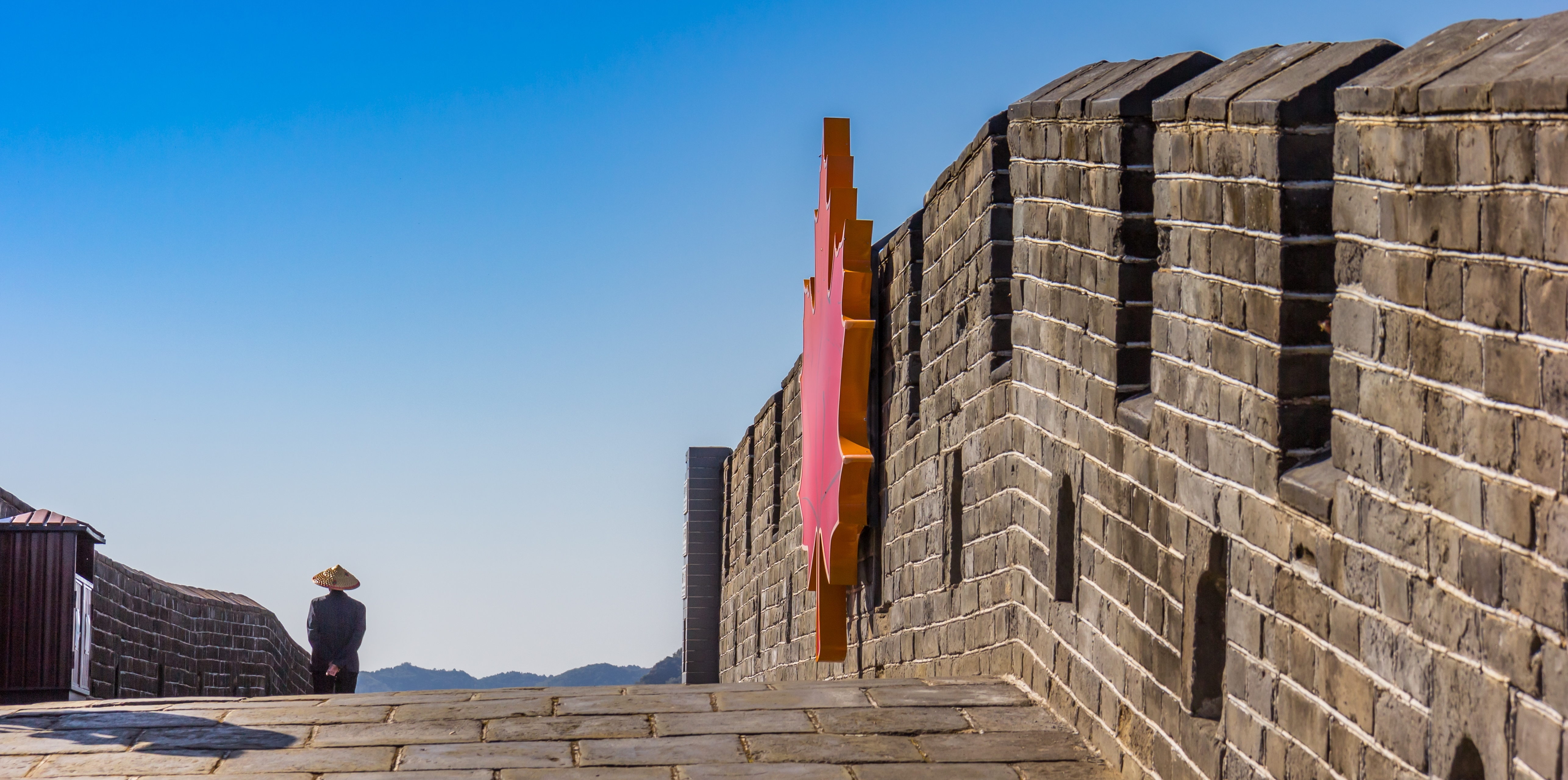 Turist på Den Kinesiske Mur med smukke efterårsløvfarver og traditionel hat