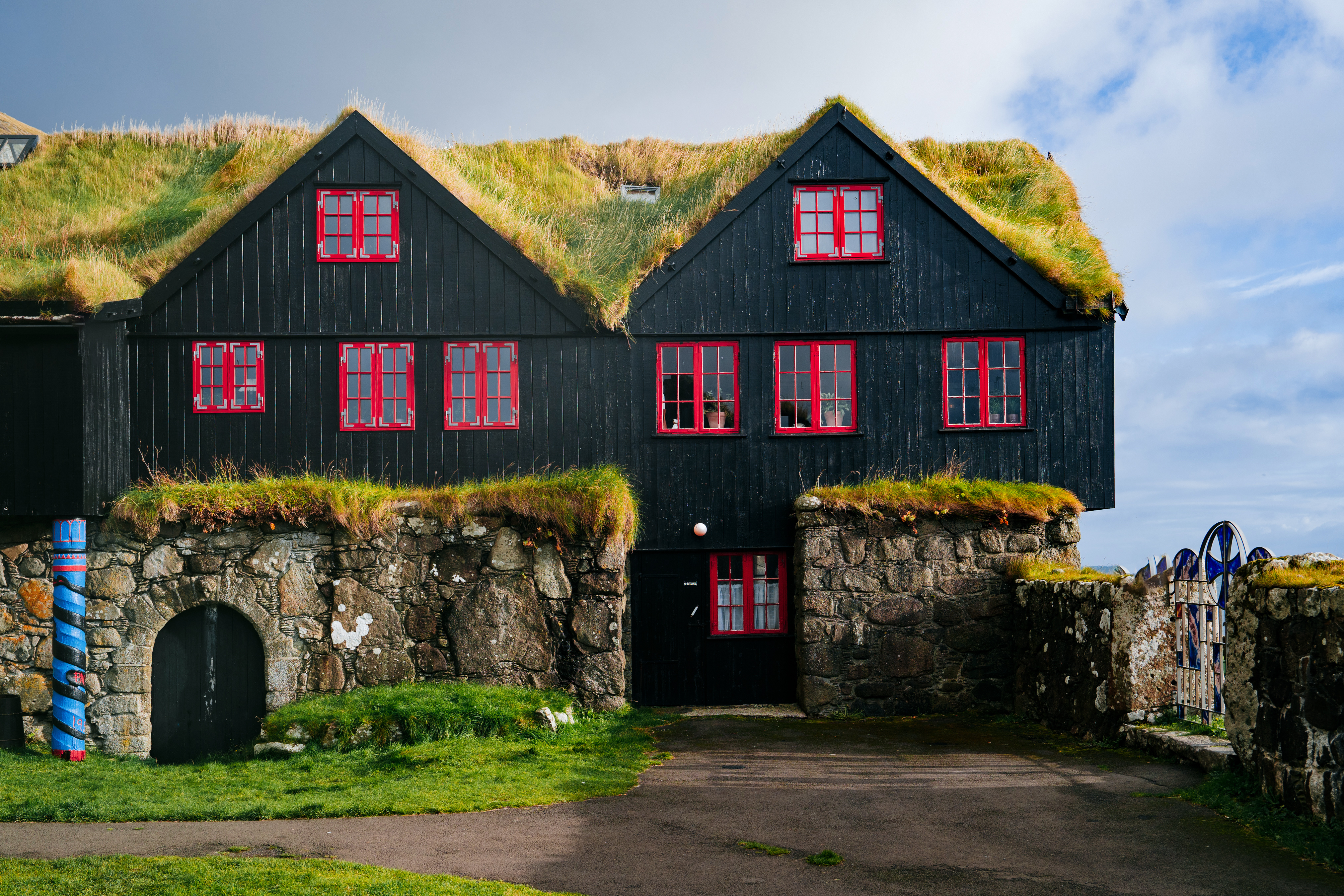 Det historiske Kirkjuboargardur museum i Kirkjubour på Færøerne med traditionelt torvtag og sorte trævægge med røde vinduesrammer