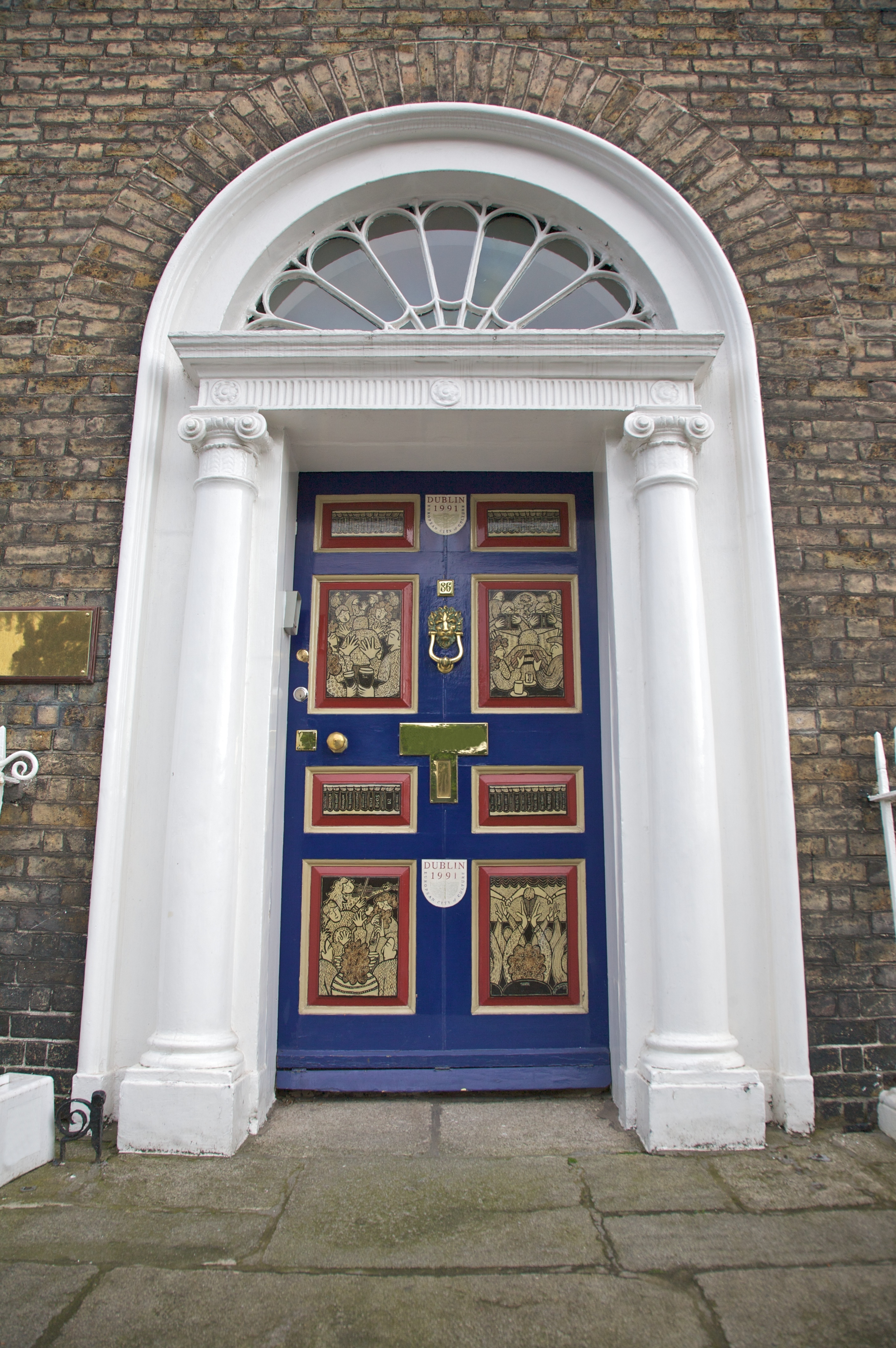 Klassisk blå dør med hvid dørkarm og buet vindue i typisk georgisk stil fra Dublin, Irland