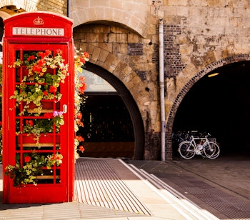 Traditionel rød engelsk telefonboks dekoreret med farverige blomster i den historiske by Bath, England