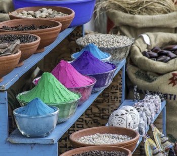 Farvestraalende udstilling af krydderier og farvepigmenter i en traditionel butik i Cochin, Kerala i Indien med bunker af gule, roede og orange krydderier