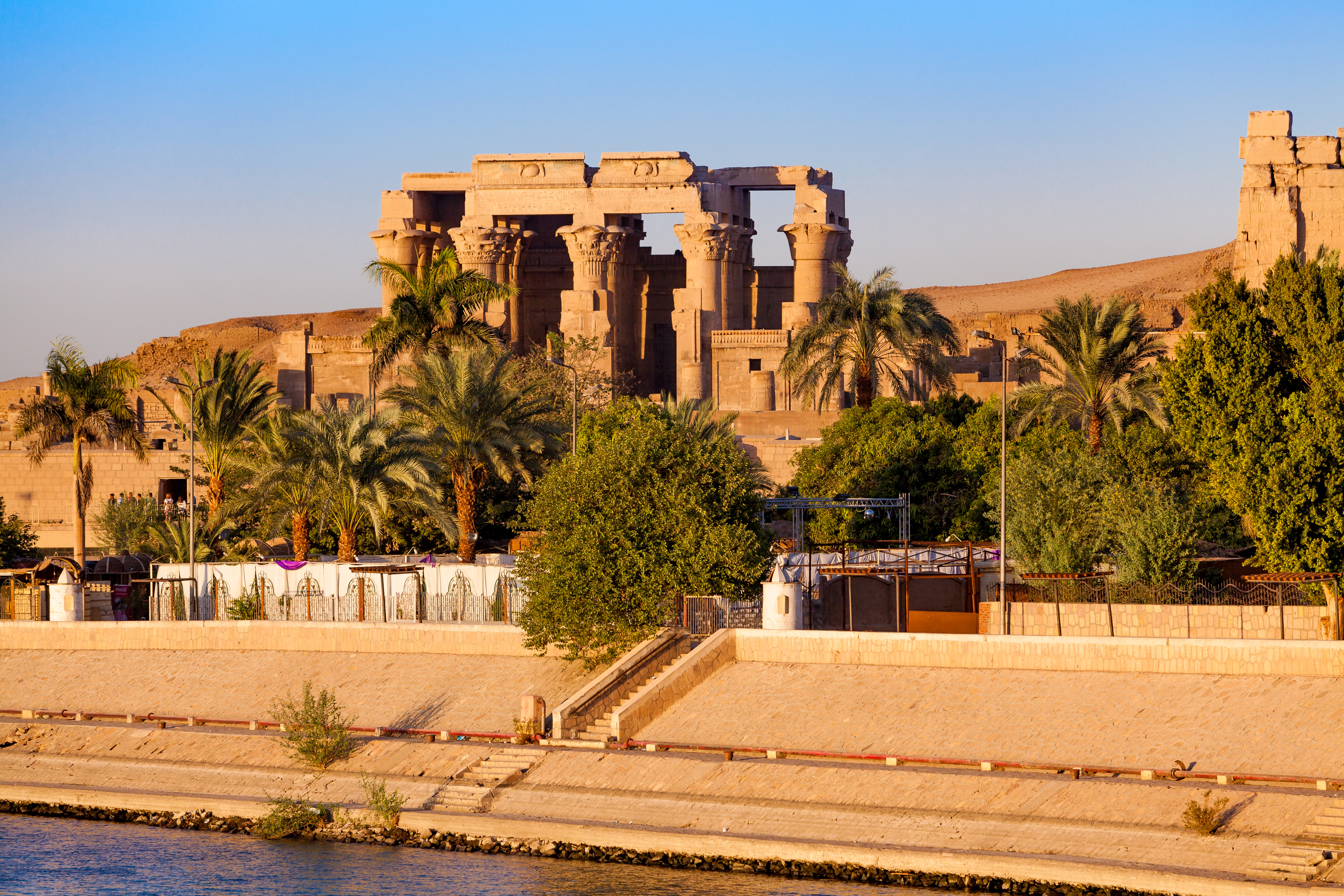 Kom Ombo templet ved solnedgang på bredden af Nilen i Egypten med antikke søjler og palmetræer