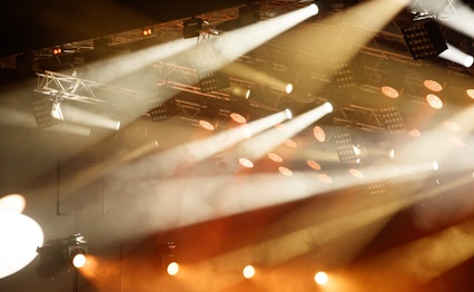 Stemningsfuld koncertscene badet i intens rød-orange belysning, der skaber den perfekte atmosfære til en uforglemmelig musikoplevelse på vores koncertrejser med professionelle lyseffekter og scenografi