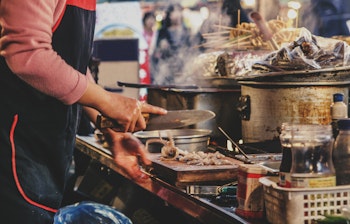 Traditionel koreansk gadekøkken i Seoul, hvor en lokal madlaver tilbereder friske retter ved en travl markedsbod