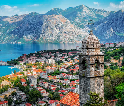 Historisk kirketårn fra Vor Frue af Lindring Kirke med udsigt over Kotors gamle bydel og den smukke bugt omgivet af imponerende bjerge i Montenegro